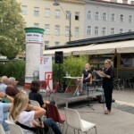 kobieta przemawia przez mikrofon w przestrzeni placu publicznego